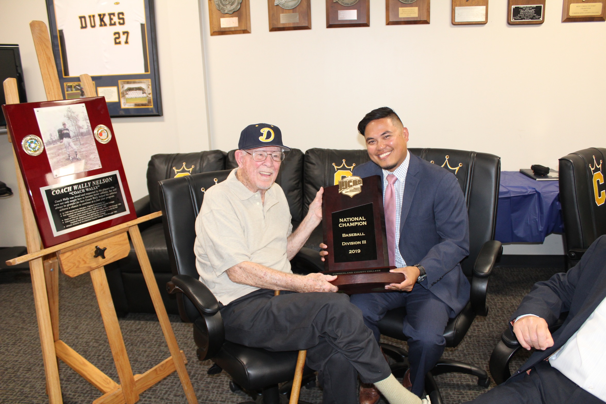 Wally Nelson with the 2019 Baseball National Championship trophy along with AD, Jonathan Dijamco.  Nelson started the baseball program at Cumberland in 1969 and was their first Head Coach.